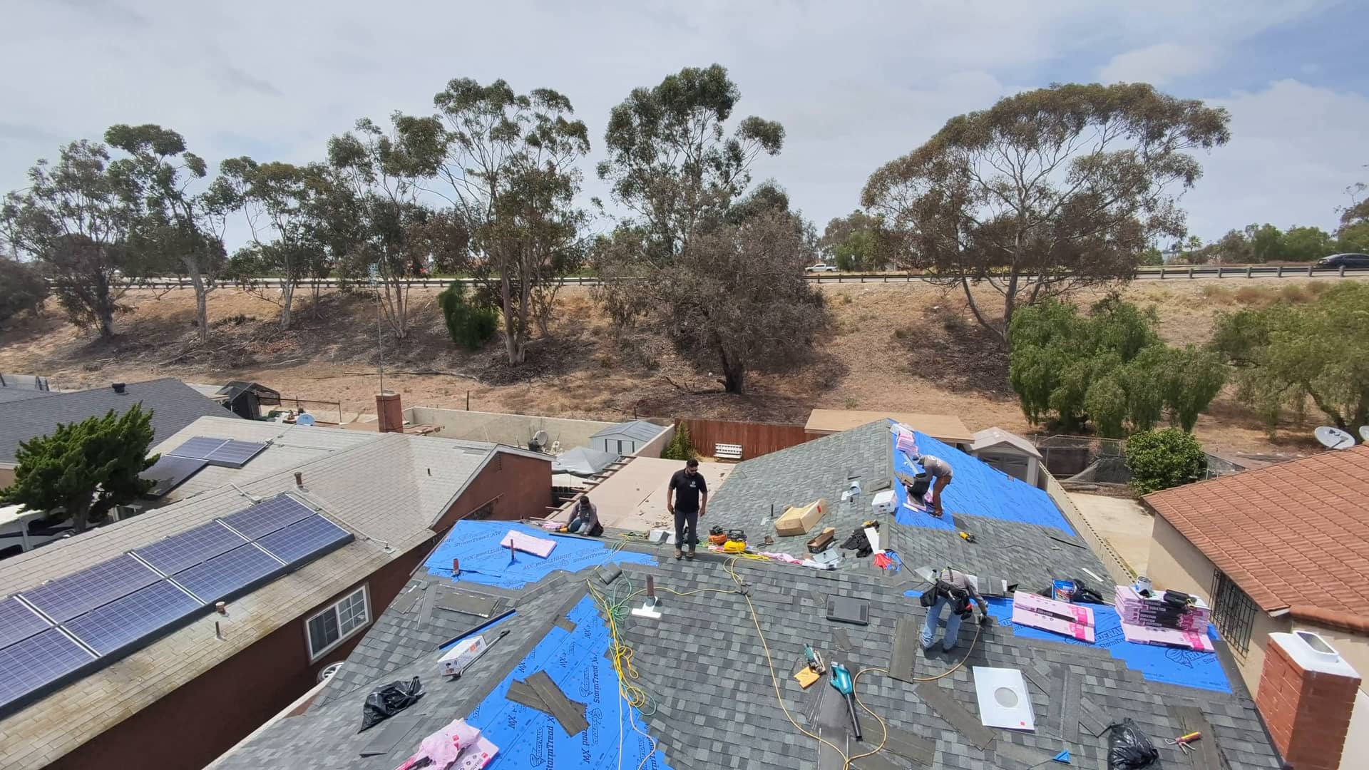 Drone view of the crew mid re-roof, underlayment down and shingles going on