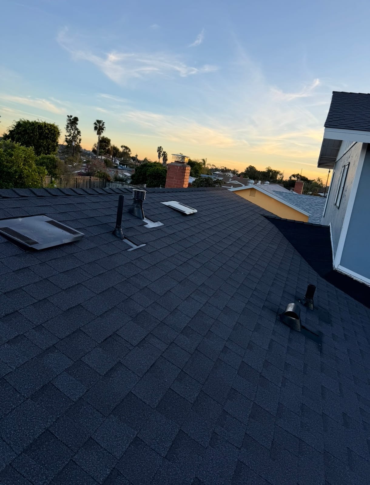 New charcoal shingles and fresh flashing details at dusk