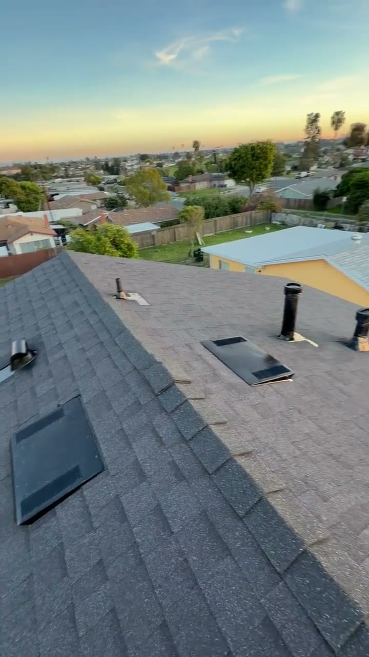 Drone pass over a finished charcoal shingle roof at dusk